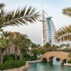 Scenic view of Burj Al Arab with surrounding palm trees and bridge in Dubai, UAE.