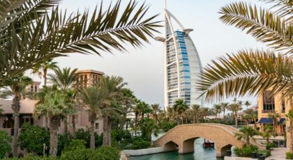 Scenic view of Burj Al Arab with surrounding palm trees and bridge in Dubai, UAE.