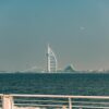 A majestic view of Burj Al Arab with the ocean in the foreground from Dubai's coastline.