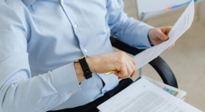 Businessman reviewing papers in office setting, highlighting analysis and attention to detail.