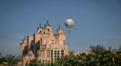View of the iconic Atlantis Hotel with a hot air balloon in a clear sky, showcasing architectural beauty.