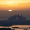A stunning sunset view of Atlantis Hotel silhouette in Dubai with a serene, golden sky backdrop.