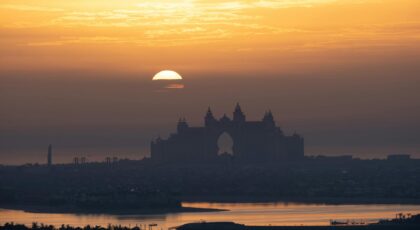 A stunning sunset view of Atlantis Hotel silhouette in Dubai with a serene, golden sky backdrop.