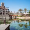 Explore the serene setting of Madinat Jumeirah Resort in Dubai, featuring traditional architecture and lush palm trees.