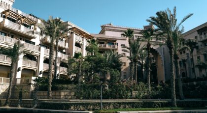 Elegant hotel surrounded by palm trees, showcasing traditional architecture under a bright blue sky.