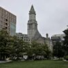 Boston's iconic Custom House Tower framed by greenery in a cityscape.
