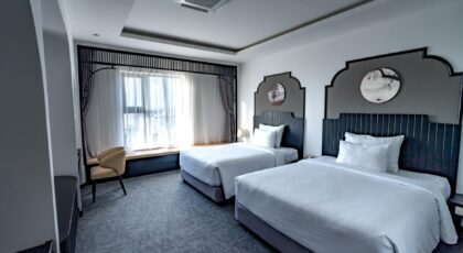 Spacious hotel room featuring two twin beds, elegant decor, and stylish furnishings.