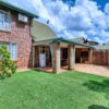 A beautiful suburban brick house with a lush green lawn and patio in Pretoria, South Africa.