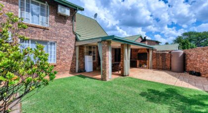 A beautiful suburban brick house with a lush green lawn and patio in Pretoria, South Africa.