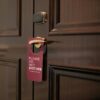 A wooden hotel door with a 'Please Do Not Disturb' sign hanging on the handle.