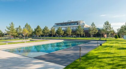 Elegant poolside at a modern resort with lush greenery and clear blue skies, ideal for luxury travel.