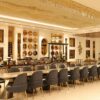Luxurious and spacious hotel dining room with elegant decor and rich golden accents, offering a lavish ambiance.