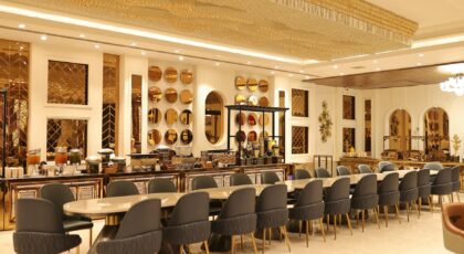 Luxurious and spacious hotel dining room with elegant decor and rich golden accents, offering a lavish ambiance.