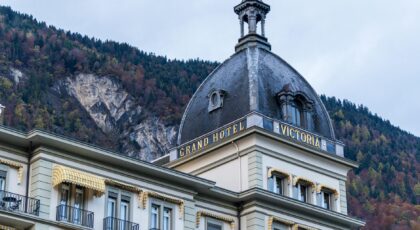 The historic Grand Hotel Victoria in Interlaken, Switzerland against a stunning alpine backdrop.