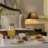 Elegant hotel room breakfast featuring pastries, orange juice, and a stylish table setting.