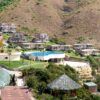 Remote settlement with contemporary villas and creative houses under straw roofs with outdoor pool located on hilly terrain on sunny day