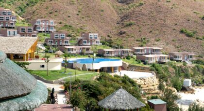 Remote settlement with contemporary villas and creative houses under straw roofs with outdoor pool located on hilly terrain on sunny day