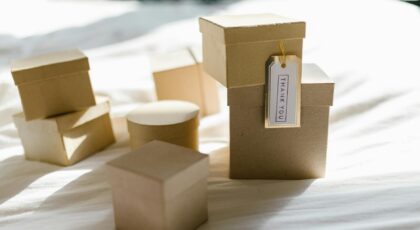 Cardboard gift boxes on a bed with thank you tag in natural light, perfect for product mockups.