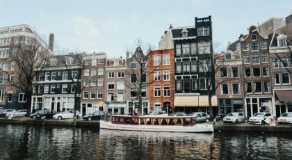 Charming Amsterdam canal scene with classic Dutch architecture and a boat cruising on the water.