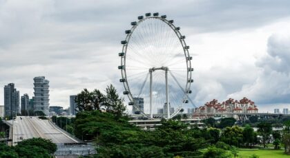 Scenic view of Singapore Flyer surrounded by greenery under a cloudy sky.