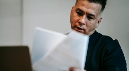 Professional man intently reviewing paperwork at his workstation indoors.