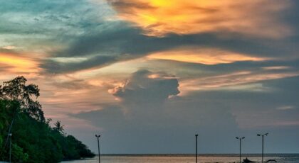 A tranquil sunset view with a jetty in Jakarta, Indonesia, showcasing vibrant skies and calm waters.