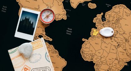 Flat lay of travel items including a map, compass, and polaroid for adventure planning.