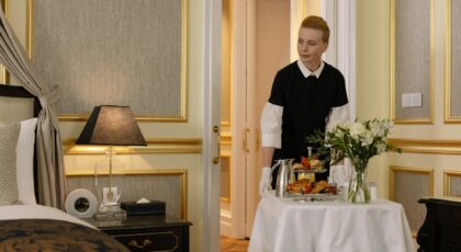 Chambermaid delivering luxury room service breakfast to a stylish hotel room, exuding comfort and hospitality.