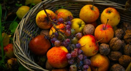Vibrant basket of apples, grapes, and walnuts, symbolizing a rich autumn harvest.