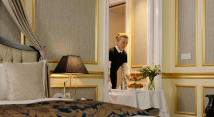 A hotel employee delivers elegant room service with a tray of breakfast in a luxurious hotel setting.