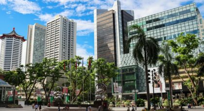 Explore the modern skyscrapers and bustling urban life of Singapore's cityscape under a bright blue sky.