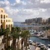 Scenic view of Hilton Malta's marina with yachts and palm trees, capturing urban luxury by the sea.