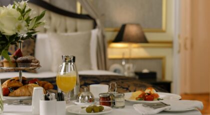 Elegant hotel room breakfast featuring pastries, orange juice, and a stylish table setting.