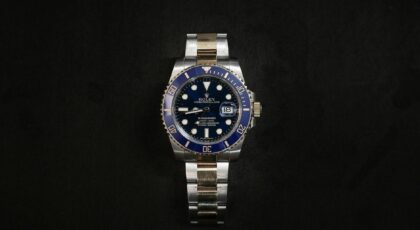 Close-up of a luxurious Rolex wristwatch on a black background.