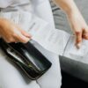 Close-up of a woman's hands managing multiple receipts taken from a black wallet.